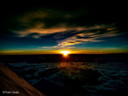 地平線から太陽が出る瞬間の山頂から撮影した写真