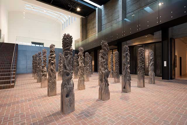 抽象的なトーテムポールのような木の彫刻が30本、会場に規則正しく配置されている作品