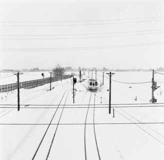雪で一面真っ白な世界に線路と遠くからやってくる汽車が映っているモノクロ写真