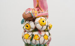 花の上に足をあげて寝る女性の陶磁器立体作品