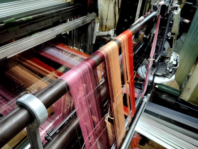 昭和初期創業の機屋で、ネクタイや袴の生地などを手がけてきた歴史を持ち、今もジャガード織機やドビー織機を用いてこだわりの織物づくりを続けている「岡村織物(有)」。